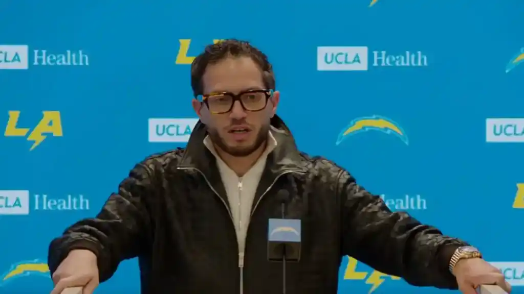 Jim Harbaugh at his introductory Los Angeles Chargers press conference wearing a black leather jacket and glasses.